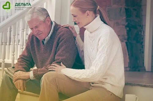 Женщина сидит на крыльце с отцом и держит его за плечо